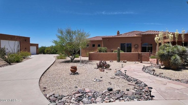 exterior space featuring stucco siding, a tiled roof, a chimney, and fence