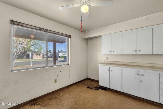 kitchen with light countertops, white cabinetry, ceiling fan, and baseboards