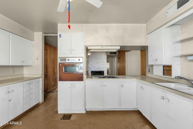 kitchen featuring oven, a sink, visible vents, white cabinets, and light countertops