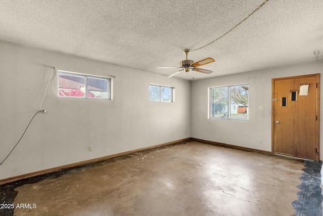 interior space featuring a ceiling fan, a textured ceiling, baseboards, and concrete flooring