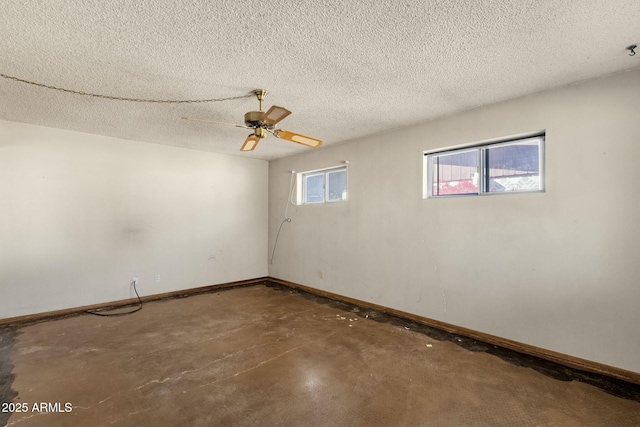 empty room featuring a textured ceiling, a ceiling fan, concrete flooring, and baseboards