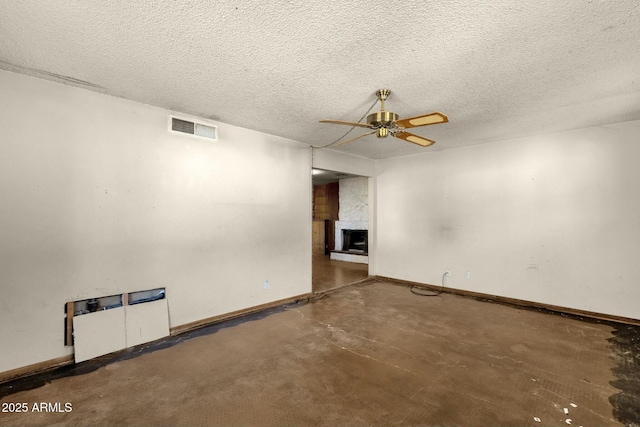 spare room featuring visible vents, concrete floors, a textured ceiling, and a fireplace