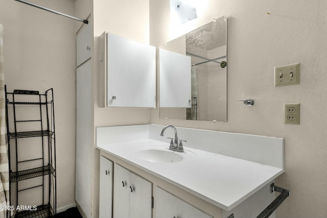 full bathroom featuring a textured wall, vanity, and walk in shower