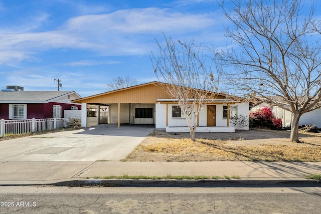 ranch-style house featuring an attached carport, concrete driveway, and fence