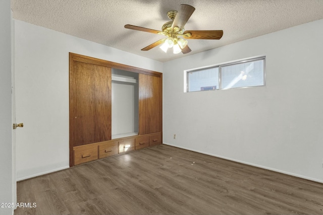 unfurnished bedroom with a closet, a textured ceiling, a ceiling fan, and wood finished floors