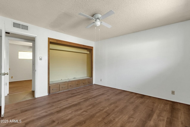 unfurnished bedroom featuring a closet, visible vents, a textured ceiling, and wood finished floors