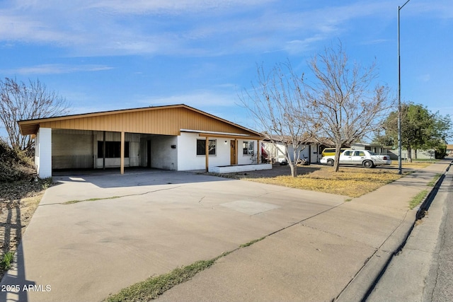 ranch-style house featuring concrete driveway and an attached carport