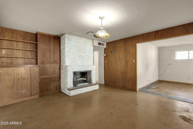 unfurnished living room featuring visible vents, wood walls, and a stone fireplace