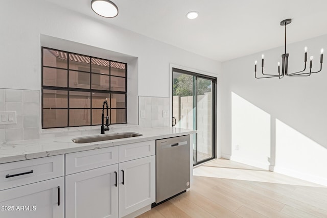 kitchen with decorative light fixtures, dishwasher, sink, white cabinets, and light stone countertops