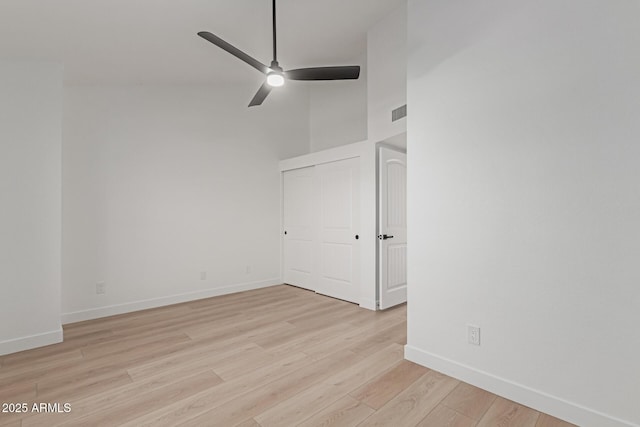 spare room with ceiling fan, a towering ceiling, and light hardwood / wood-style floors