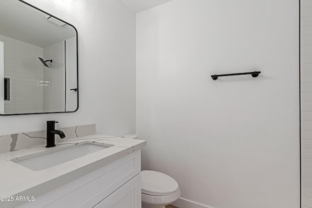 bathroom featuring tiled shower, vanity, and toilet