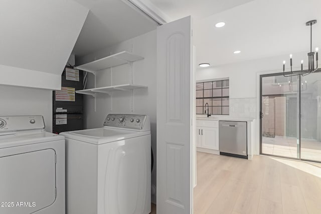 clothes washing area featuring separate washer and dryer, sink, a notable chandelier, and light wood-type flooring