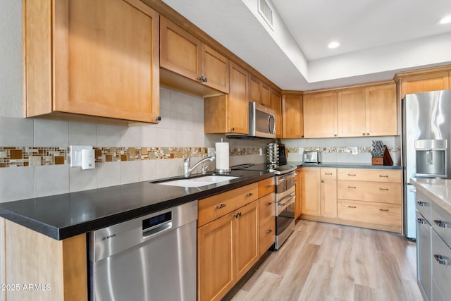 kitchen featuring sink, stainless steel appliances, tasteful backsplash, and light hardwood / wood-style flooring