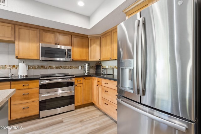 kitchen with decorative backsplash, light hardwood / wood-style floors, and appliances with stainless steel finishes