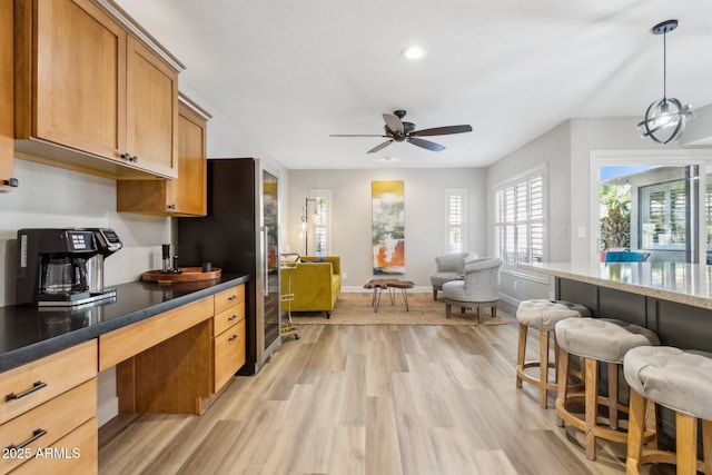 kitchen featuring ceiling fan, pendant lighting, light hardwood / wood-style floors, black refrigerator, and built in desk