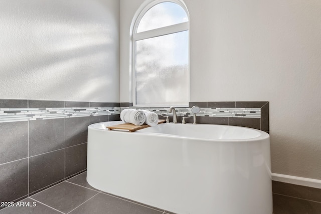 bathroom featuring tile patterned flooring, a bath, and tile walls