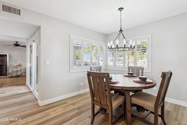 dining room with ceiling fan with notable chandelier and hardwood / wood-style flooring