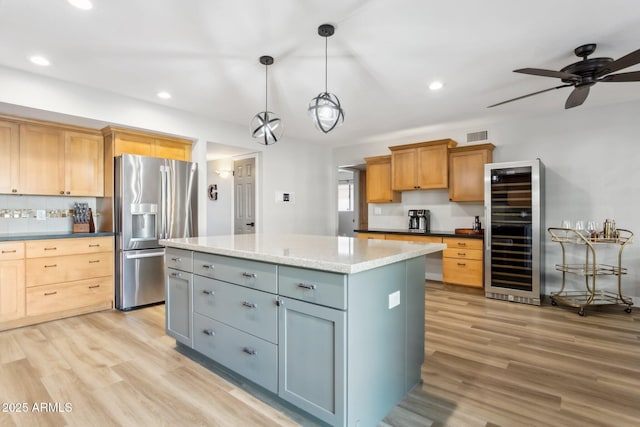 kitchen featuring gray cabinetry, a center island, stainless steel refrigerator with ice dispenser, wine cooler, and light stone countertops