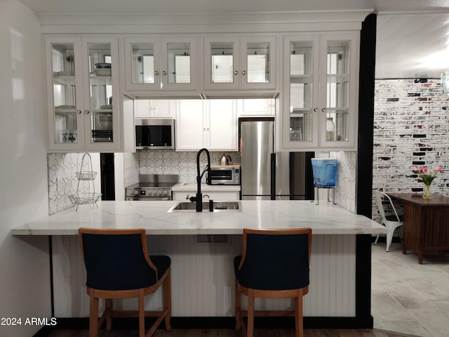 kitchen with a breakfast bar area, kitchen peninsula, white cabinetry, and appliances with stainless steel finishes