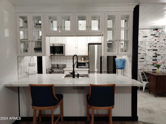 3119 W Cochise Dr Unit 225, Phoenix, AZ 85051 - kitchen featuring decorative backsplash, a peninsula, stainless steel appliances, white cabinetry, and a sink
