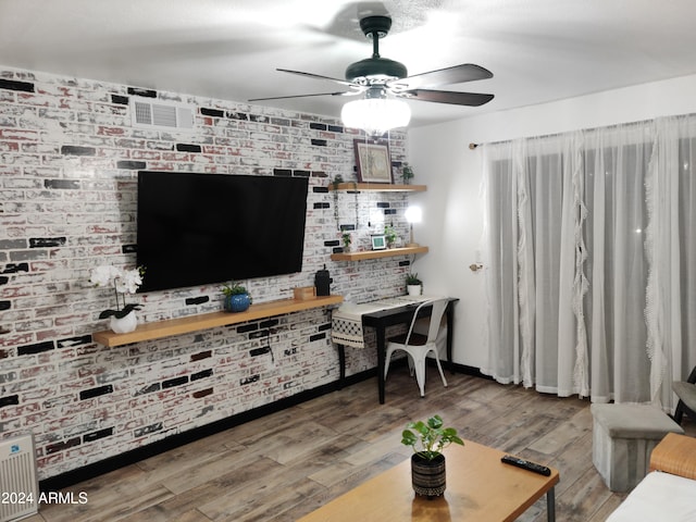 living room featuring ceiling fan, brick wall, and hardwood / wood-style flooring