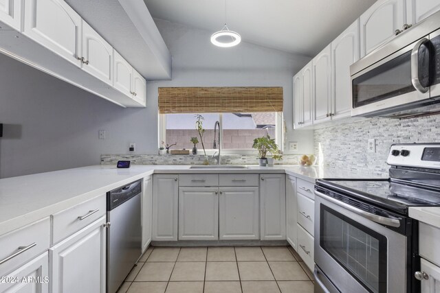 kitchen with stainless steel appliances, vaulted ceiling, sink, light tile patterned floors, and white cabinetry