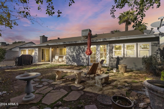 back house at dusk with french doors and a patio area