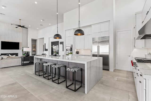 kitchen with a towering ceiling, appliances with stainless steel finishes, a spacious island, decorative light fixtures, and a breakfast bar