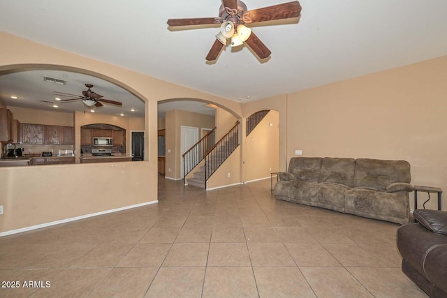 16112 W Durango St, Goodyear, AZ 85338 - living room with ceiling fan, visible vents, arched walkways, stairway, and light tile patterned flooring