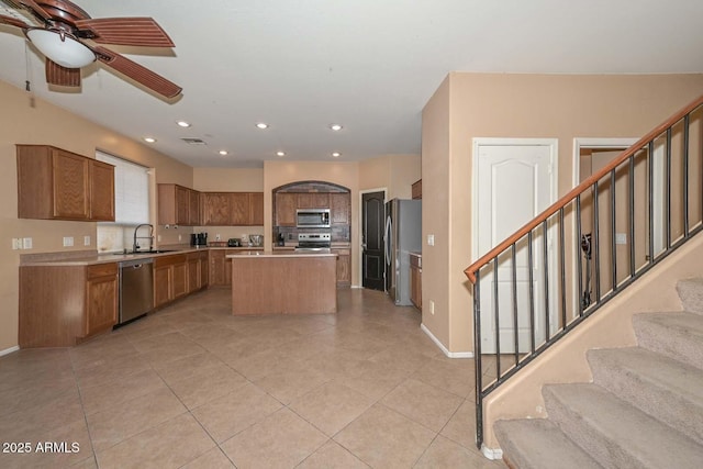 16112 W Durango St, Goodyear, AZ 85338 - kitchen with brown cabinetry, ceiling fan, a center island, appliances with stainless steel finishes, and light tile patterned floors