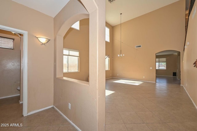 16112 W Durango St, Goodyear, AZ 85338 - empty room featuring a towering ceiling, visible vents, arched walkways, baseboards, and tile patterned floors
