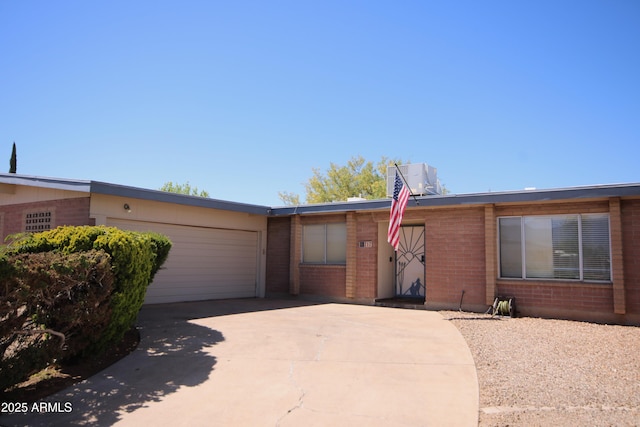 ranch-style home featuring a garage, central air condition unit, driveway, and brick siding