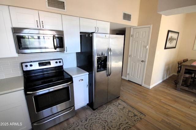 kitchen with visible vents, appliances with stainless steel finishes, backsplash, and wood finished floors