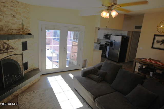 living room featuring french doors, a fireplace, and a ceiling fan