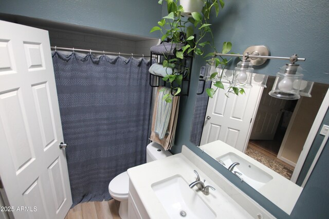 full bath featuring a sink, toilet, wood finished floors, and a shower with shower curtain