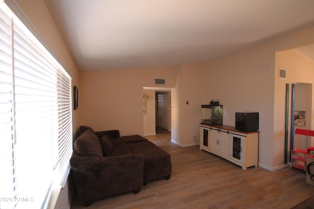 living room with light wood-style floors, baseboards, and visible vents