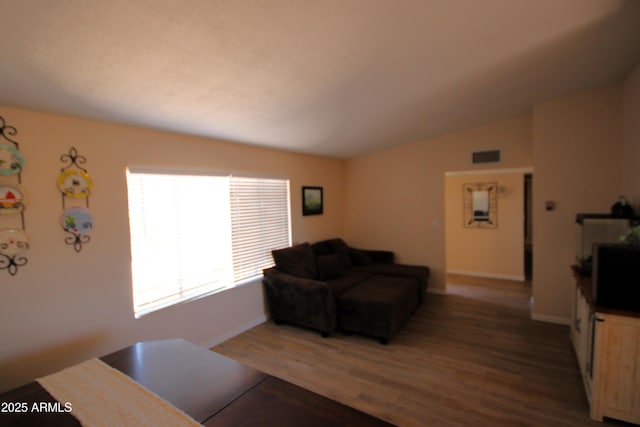 living area with baseboards, wood finished floors, and vaulted ceiling