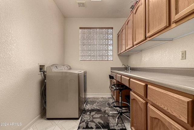 laundry room with cabinets, independent washer and dryer, and sink