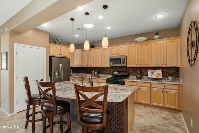 kitchen featuring hanging light fixtures, stainless steel appliances, light stone countertops, and a center island with sink