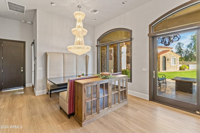 interior space featuring a chandelier, light wood-type flooring, visible vents, and baseboards