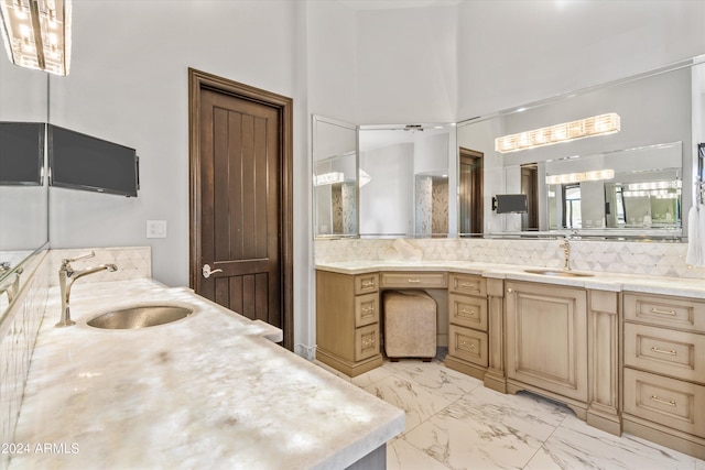 full bath with marble finish floor, two vanities, and a sink