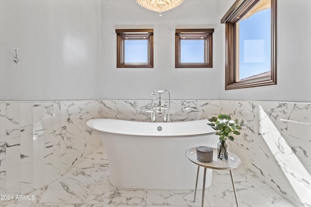 full bathroom with a freestanding bath, marble finish floor, a wainscoted wall, and tile walls