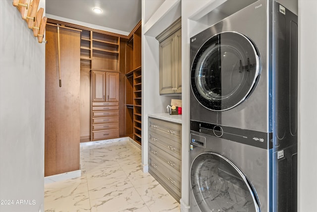 washroom with marble finish floor, cabinet space, and stacked washer and clothes dryer