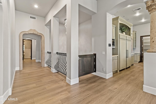 corridor featuring arched walkways, light wood-style flooring, and visible vents