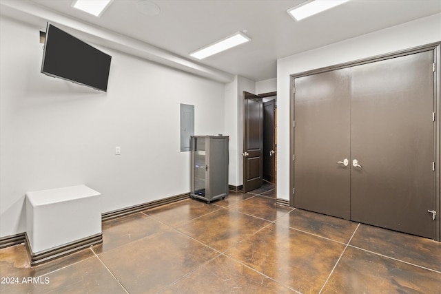 unfurnished bedroom featuring concrete flooring, a closet, and electric panel