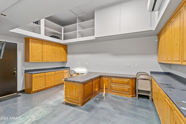 kitchen with finished concrete flooring, a peninsula, brown cabinetry, and built in desk