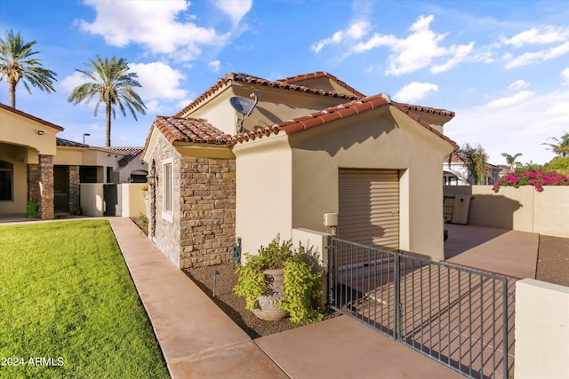 view of front of house featuring a garage, a tile roof, fence private yard, a front lawn, and stucco siding