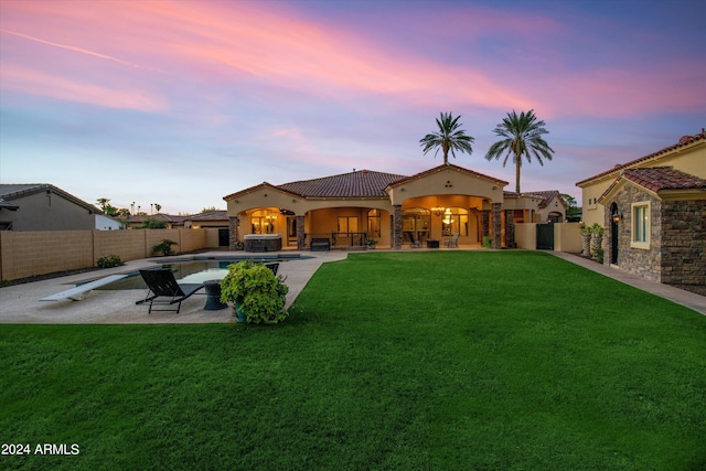 back of property at dusk with a fenced in pool, a patio area, a lawn, and a fenced backyard