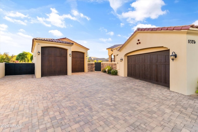 garage with a gate, fence, and decorative driveway