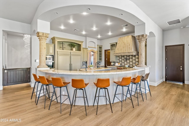 kitchen with light wood-style flooring, visible vents, a breakfast bar area, and built in appliances